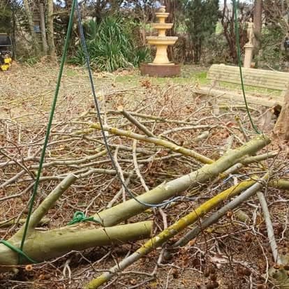 Branchage coupé rassemblé sur une pelouse, élingues déployées, avant passage au broyeur